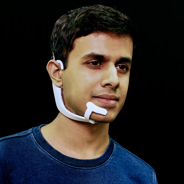 Man wearing a white device on his face that similars the microphone of a headset.