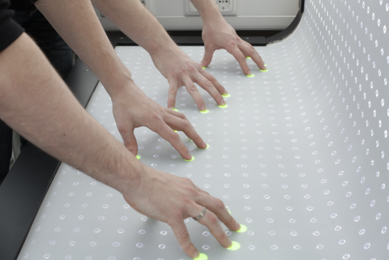 Two sets of hands using the bend desk with their finger tips.
